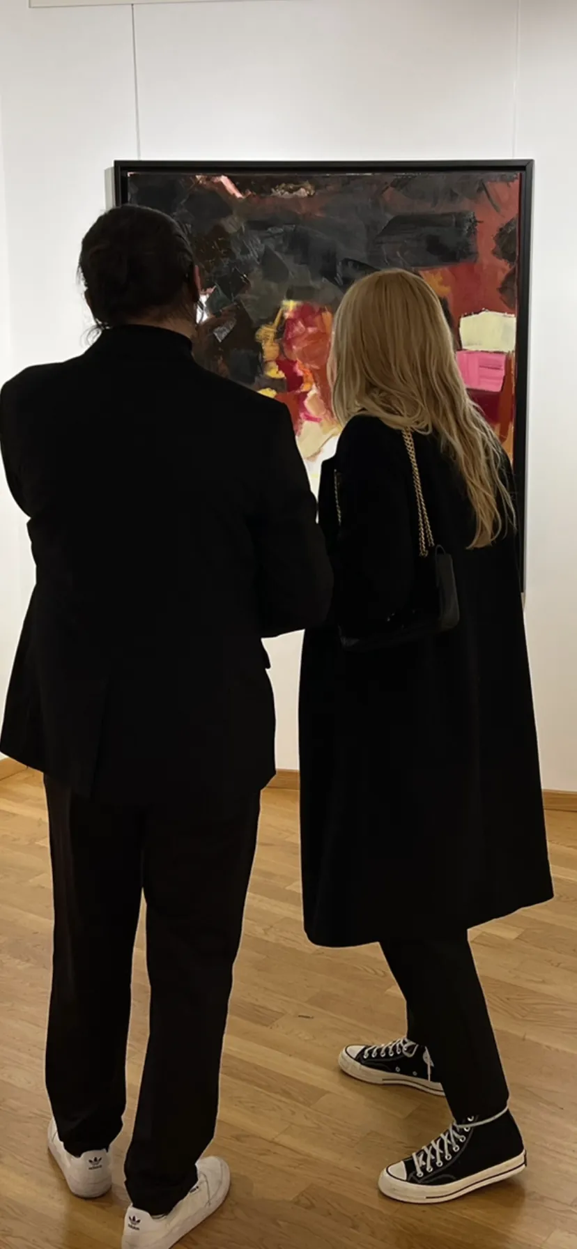 Deux personnes vues de dos devant une œuvre dans une exposition
