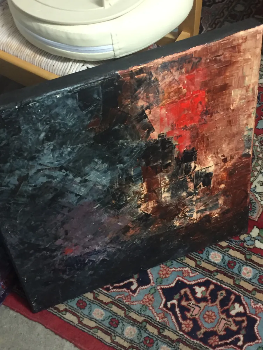 Grande toile noire et rouge appuyée dans une pièce