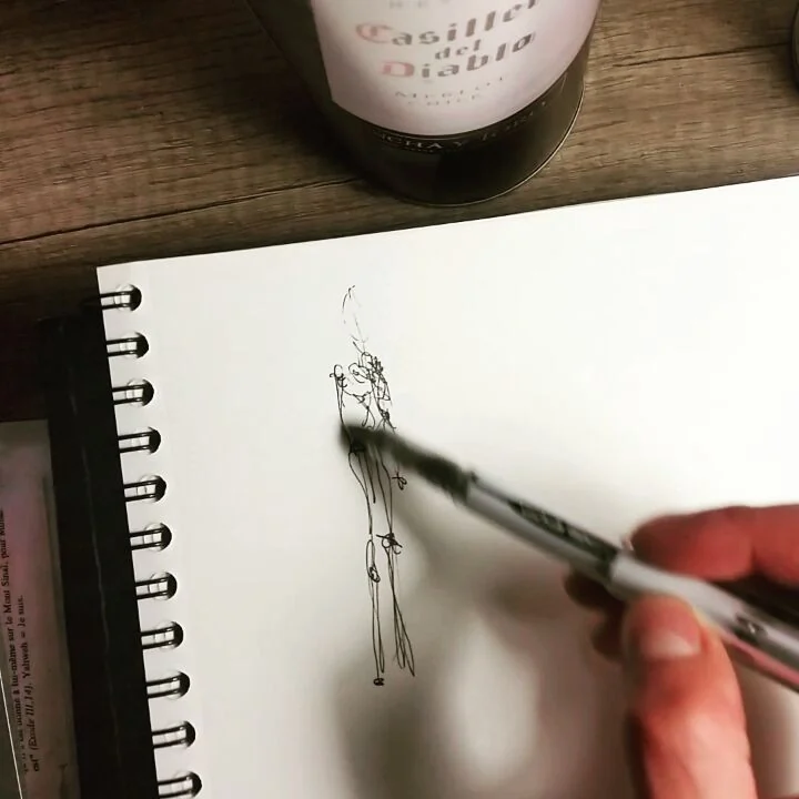 Une main dessine une figure dans un carnet à spirale