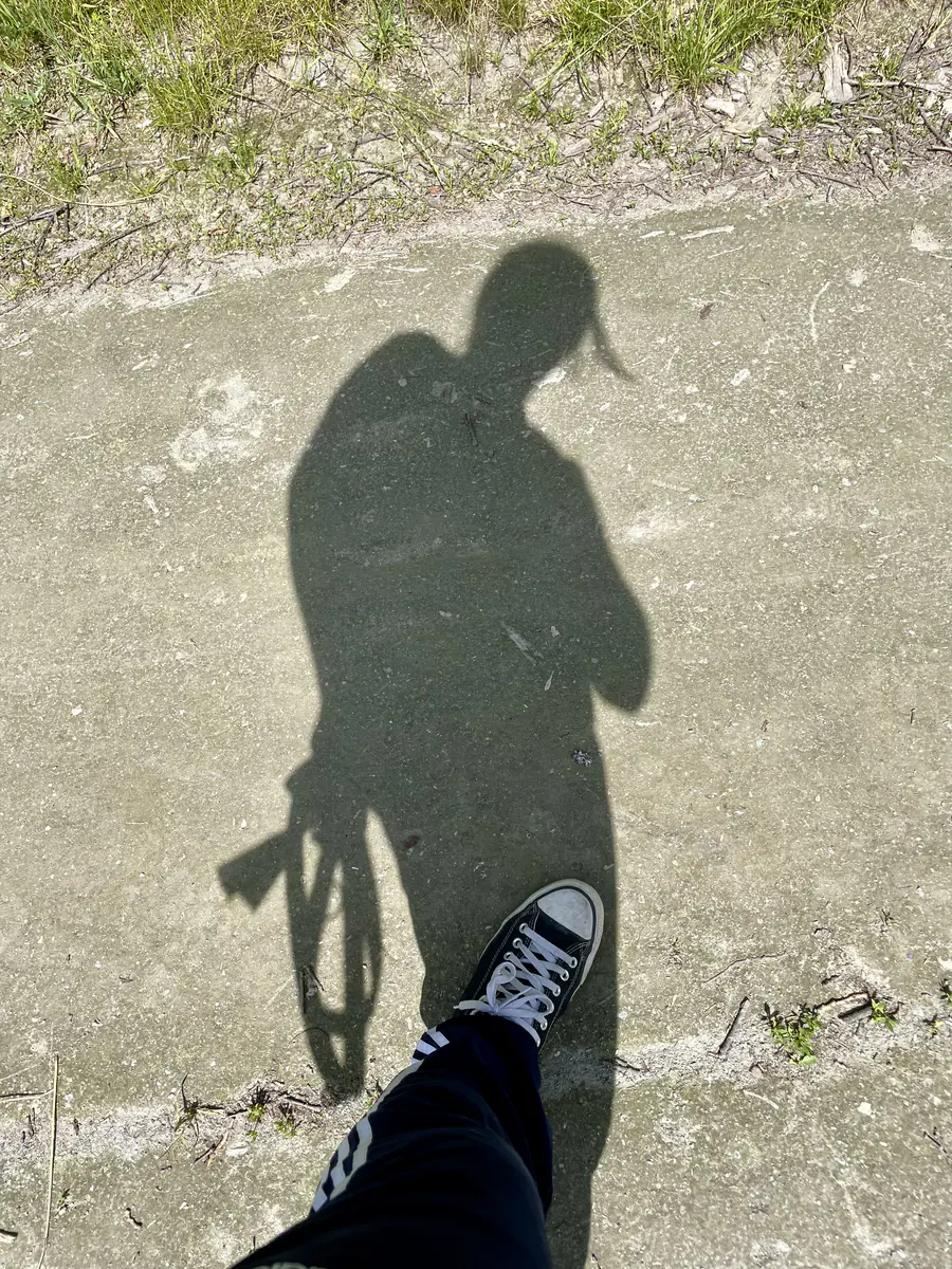 Une ombre au sol, un pied dans le cadre